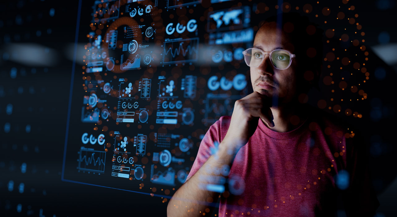 A person in glasses and a pink shirt thoughtfully analyzes digital data on a transparent screen